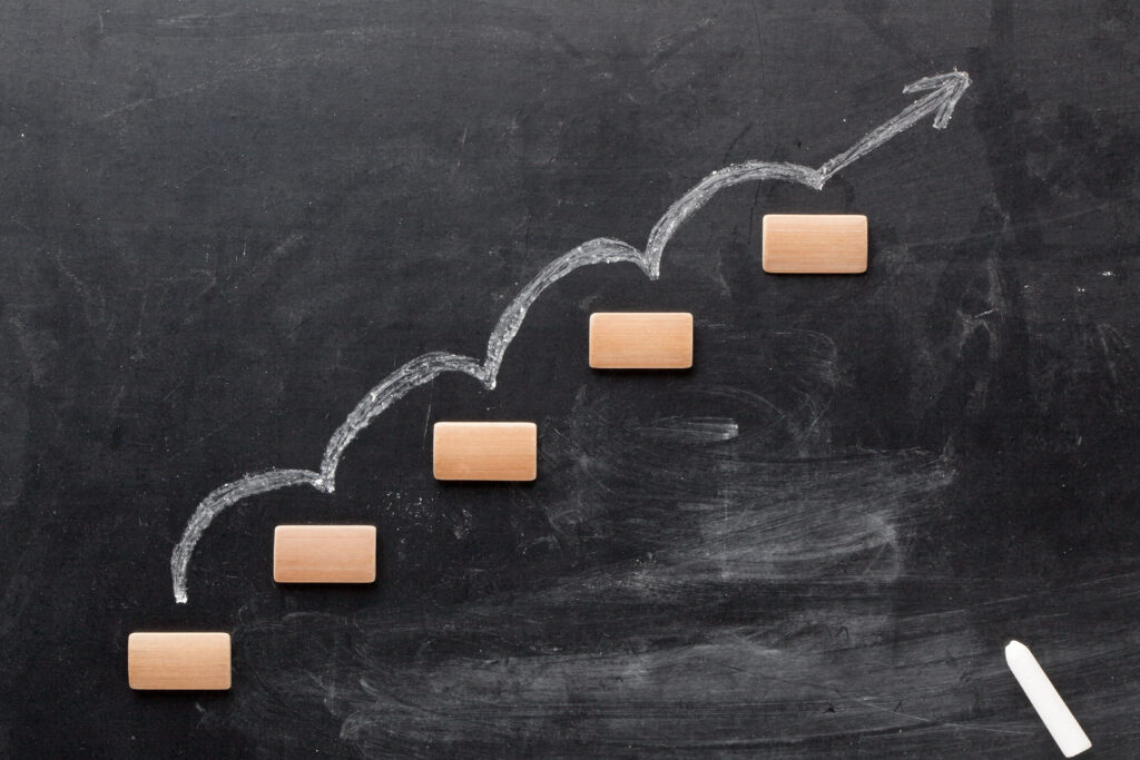 Rising arrow on staircase graphical representation of the process with chalk on blackboard. Step by step